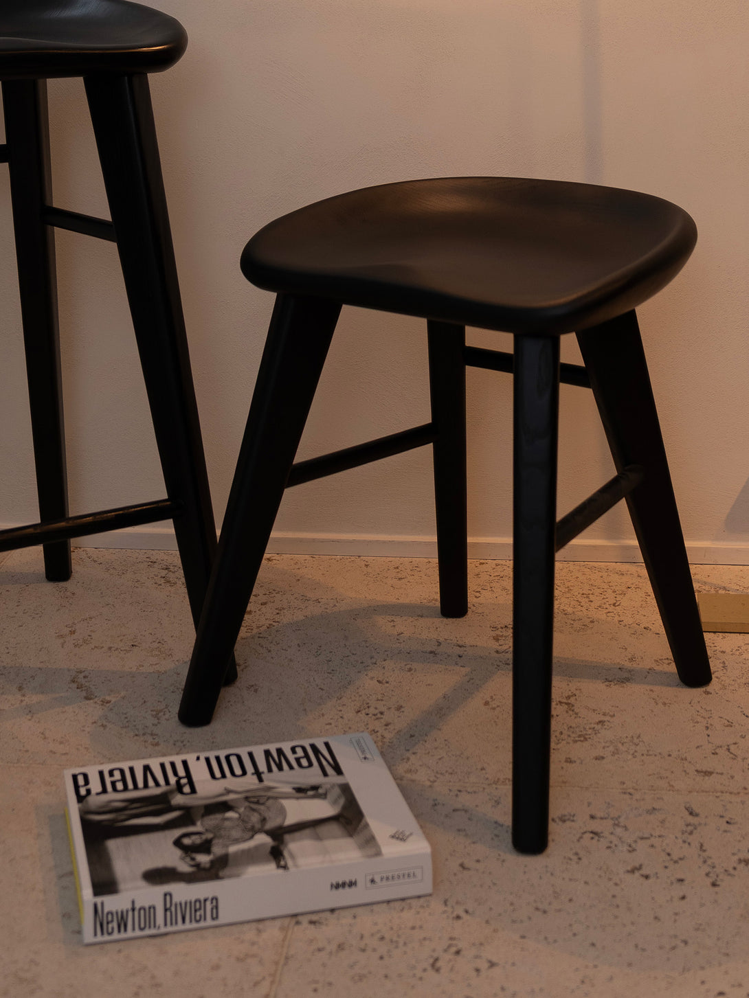 Small black Ollie stool — sculpted wooden seat with timeless, minimal lines.