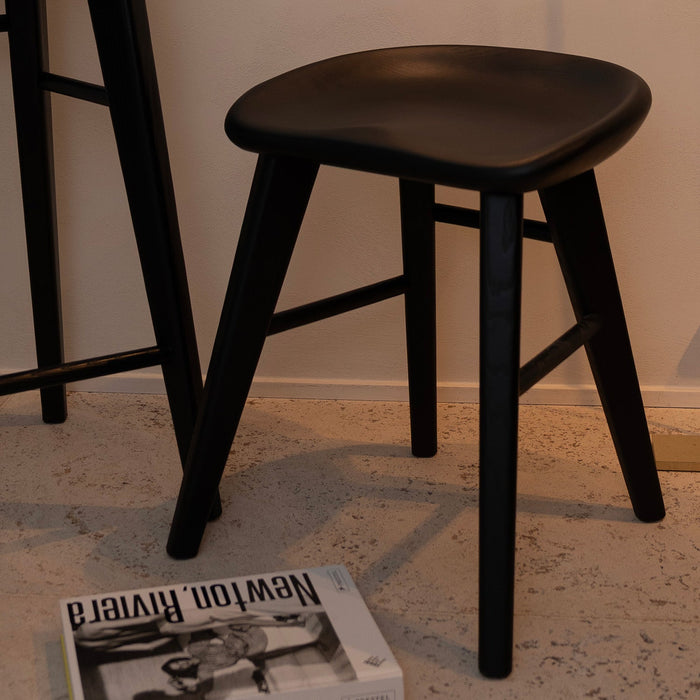 Small black Ollie stool — sculpted wooden seat with timeless, minimal lines.