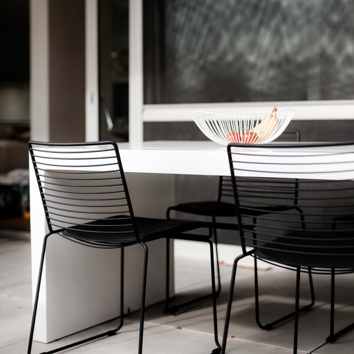 The back view of a Willow wire chair where you see the black and steel frame and backrest