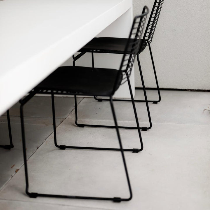 The side view of two black Willow chairs standing outside at a white dining table